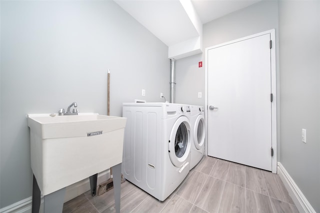 laundry area featuring laundry area, baseboards, washer and clothes dryer, and a sink