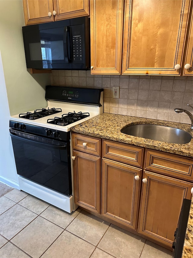 kitchen featuring sink, gas range, light tile patterned floors, light stone countertops, and decorative backsplash