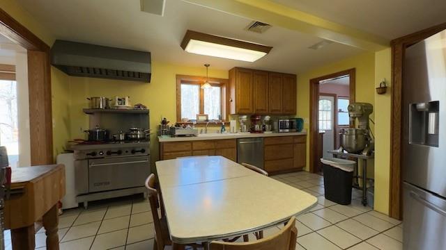 kitchen with stainless steel appliances, sink, pendant lighting, and light tile patterned floors