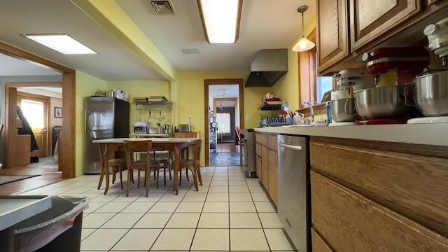 kitchen with hanging light fixtures, light tile patterned floors, exhaust hood, and appliances with stainless steel finishes