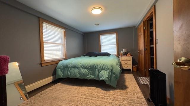 bedroom with dark wood-type flooring, a baseboard radiator, and radiator heating unit