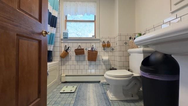 bathroom featuring baseboard heating, toilet, tile patterned flooring, and tile walls