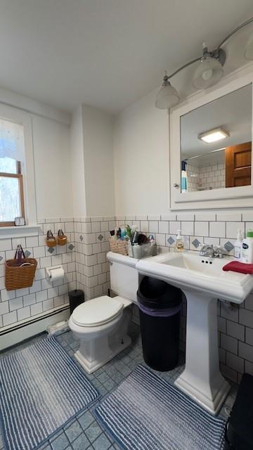 bathroom with baseboard heating, tile patterned floors, toilet, and tile walls