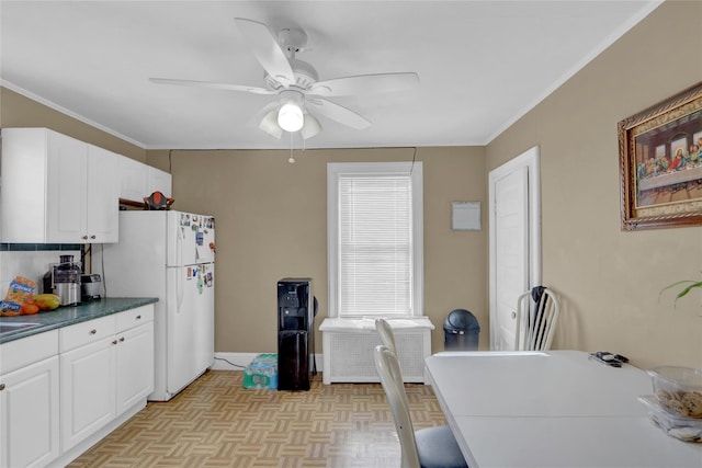 kitchen with white cabinetry, ornamental molding, white fridge, ceiling fan, and light parquet floors