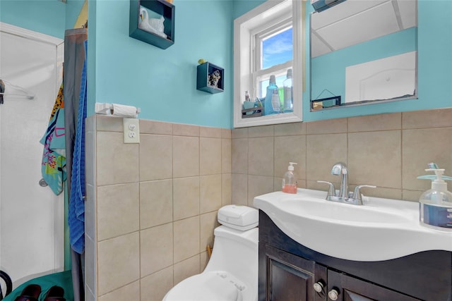 bathroom with vanity, toilet, and tile walls