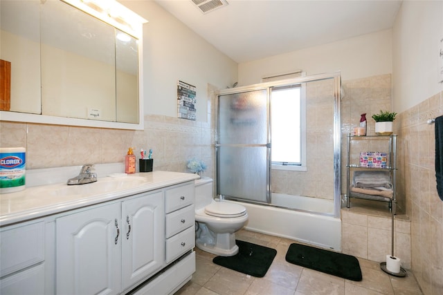 full bathroom featuring tile patterned floors, toilet, combined bath / shower with glass door, tile walls, and vanity