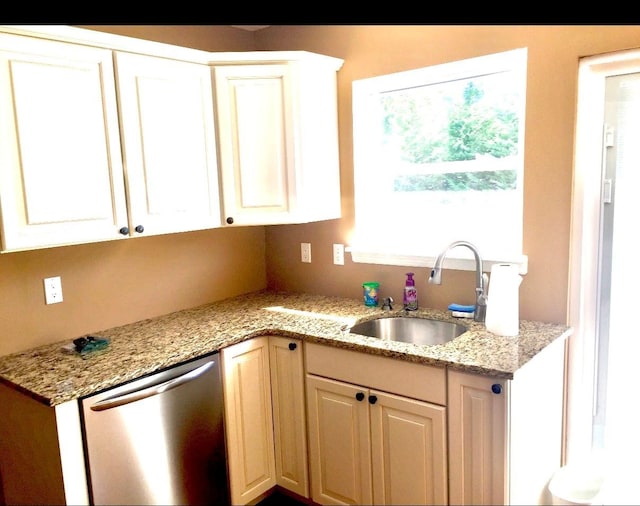 kitchen featuring stainless steel dishwasher, light stone countertops, and sink