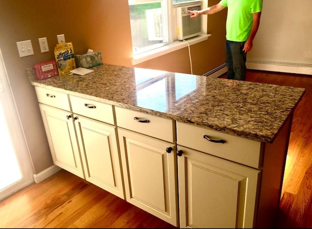 kitchen featuring light stone countertops, light hardwood / wood-style floors, and cream cabinetry