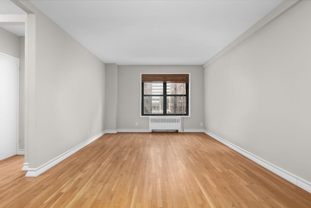 unfurnished room with radiator heating unit and light hardwood / wood-style floors