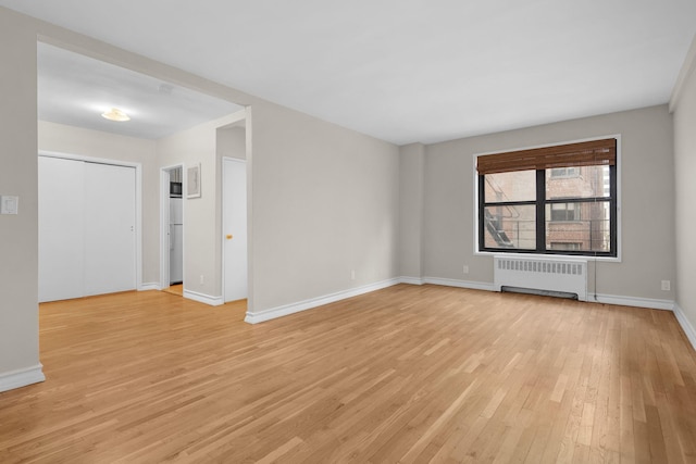 spare room featuring radiator heating unit and light hardwood / wood-style flooring