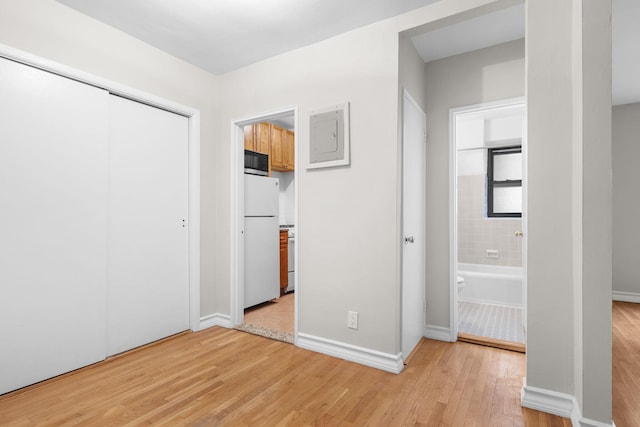 unfurnished bedroom featuring a closet, ensuite bathroom, white fridge, and light hardwood / wood-style flooring