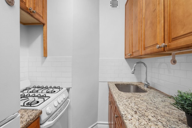 kitchen with light stone counters, sink, white appliances, and tasteful backsplash