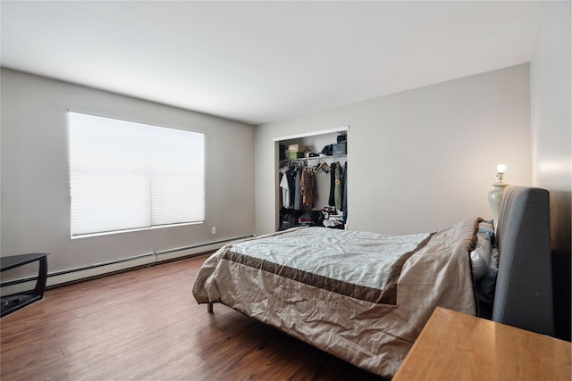 bedroom featuring a baseboard heating unit, hardwood / wood-style floors, and a closet