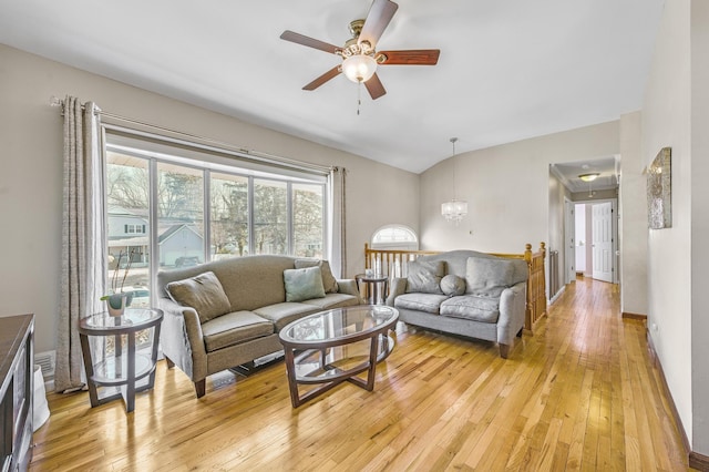 living room with ceiling fan with notable chandelier, vaulted ceiling, and light hardwood / wood-style floors