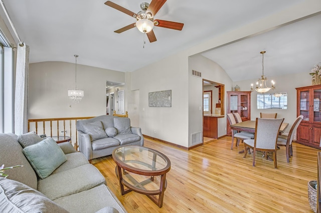 living room with vaulted ceiling, ceiling fan with notable chandelier, and light hardwood / wood-style floors