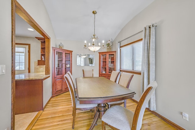 dining room featuring lofted ceiling, an inviting chandelier, and light hardwood / wood-style flooring