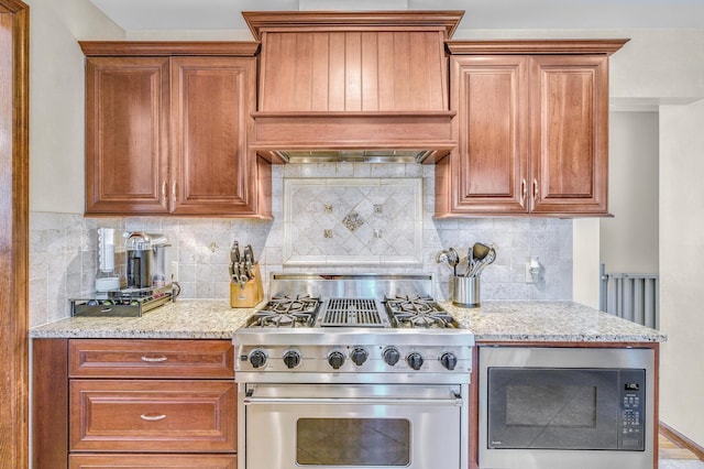 kitchen featuring built in microwave, high end stainless steel range, light stone counters, custom range hood, and backsplash