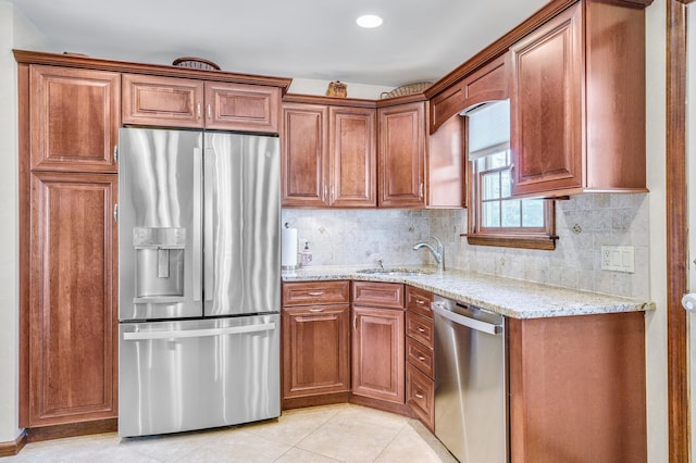 kitchen with appliances with stainless steel finishes, sink, light stone counters, and decorative backsplash