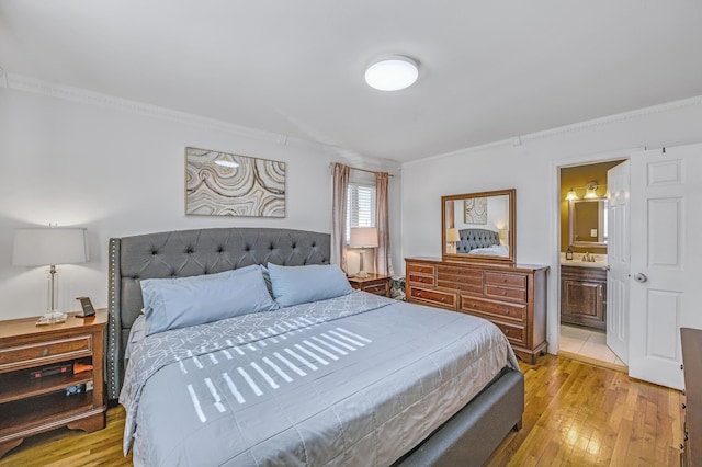 bedroom featuring ornamental molding, sink, ensuite bath, and light hardwood / wood-style flooring