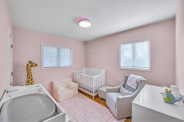 bedroom featuring a nursery area and light hardwood / wood-style flooring