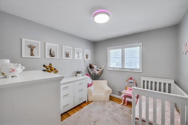 bedroom with a nursery area and light hardwood / wood-style flooring