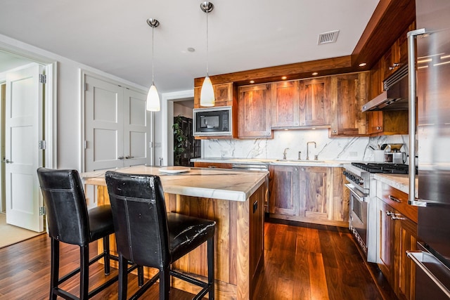 kitchen featuring dark hardwood / wood-style floors, a center island, sink, and premium appliances