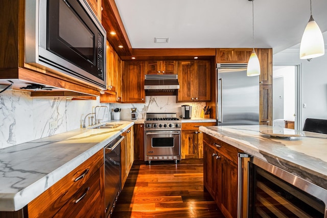 kitchen featuring dark wood-type flooring, sink, built in appliances, hanging light fixtures, and beverage cooler