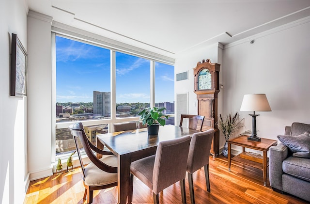 dining space featuring expansive windows, crown molding, and light hardwood / wood-style flooring