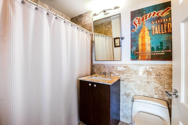 bathroom with walk in shower, vanity, toilet, and tile walls