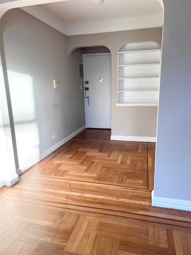 unfurnished room with parquet floors and built in shelves