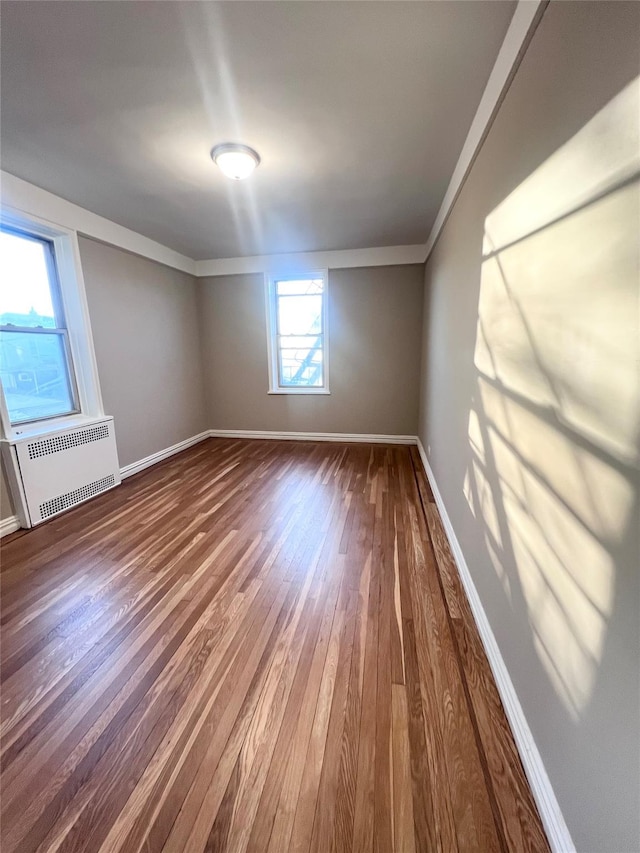 spare room with hardwood / wood-style floors, radiator heating unit, and ornamental molding