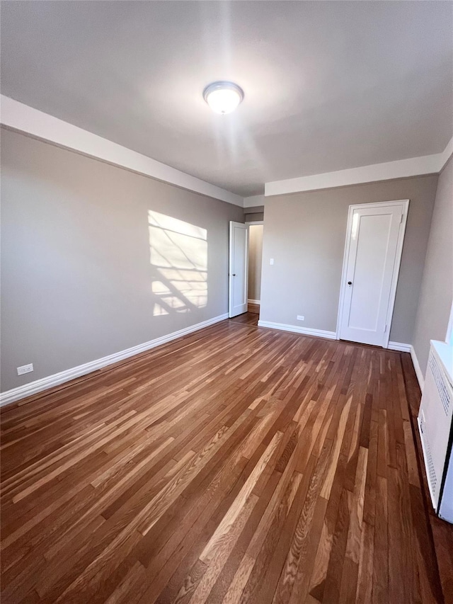 interior space with dark hardwood / wood-style flooring and heating unit