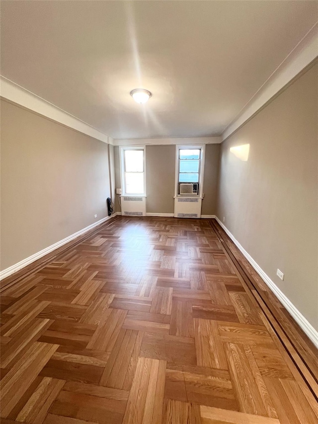 spare room with cooling unit, parquet flooring, crown molding, and radiator