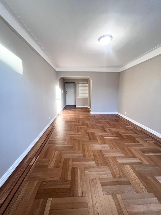 unfurnished room with crown molding and parquet flooring