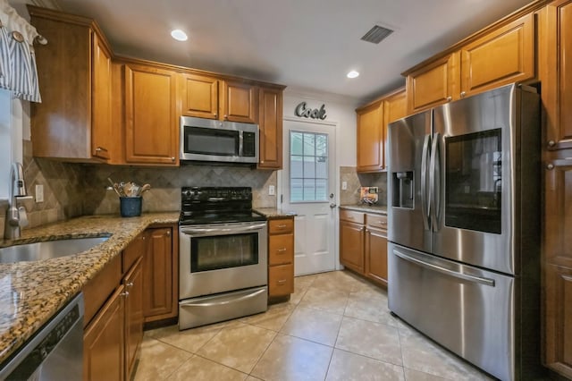 kitchen with light tile patterned flooring, sink, decorative backsplash, light stone counters, and stainless steel appliances