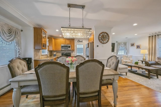 dining space featuring a baseboard radiator, plenty of natural light, sink, and light wood-type flooring