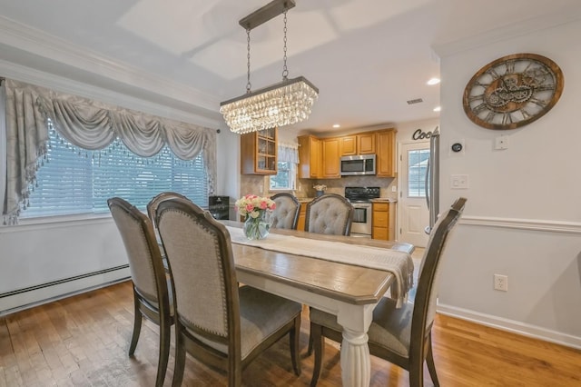 dining space featuring ornamental molding, a baseboard radiator, and light hardwood / wood-style flooring