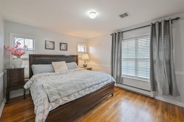 bedroom with light hardwood / wood-style flooring and a baseboard radiator