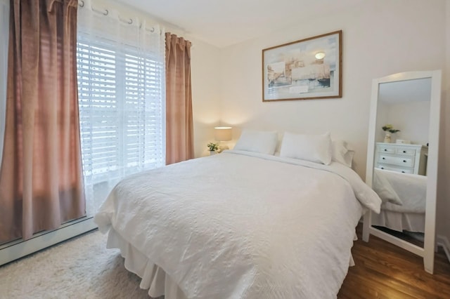 bedroom with multiple windows, dark hardwood / wood-style flooring, and baseboard heating