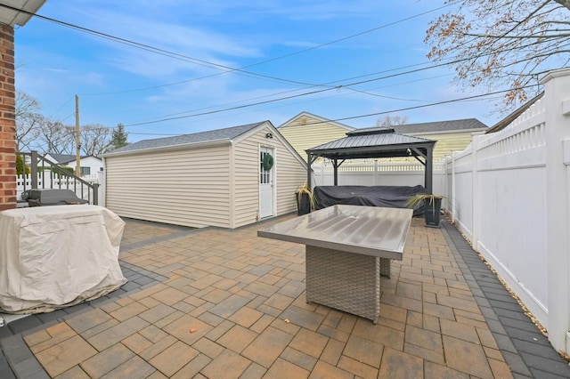 view of patio / terrace with a hot tub, a gazebo, and an outbuilding