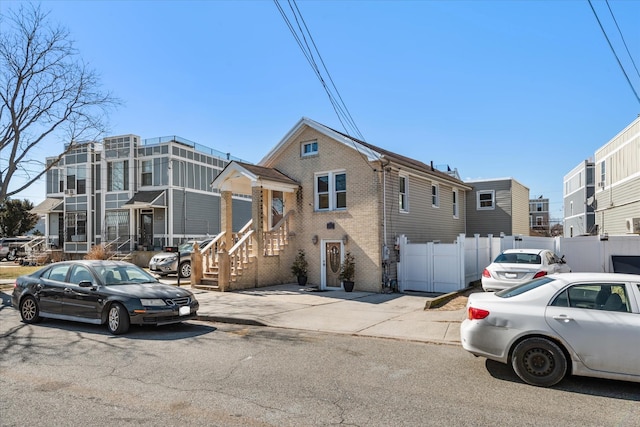 view of property with brick siding, a residential view, and fence