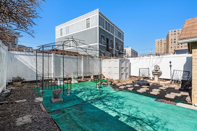 view of patio with an outdoor structure, a fenced backyard, and a shed