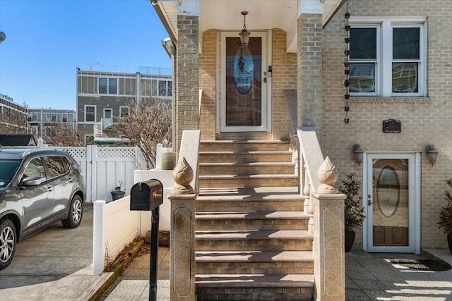 entrance to property featuring brick siding and fence