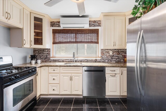 kitchen featuring a sink, appliances with stainless steel finishes, cream cabinets, a wall mounted AC, and dark tile patterned flooring