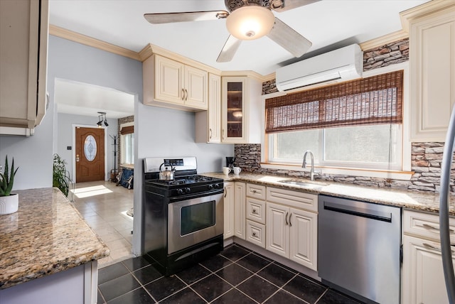 kitchen featuring backsplash, an AC wall unit, cream cabinets, stainless steel appliances, and a sink