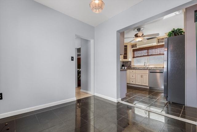 kitchen featuring a ceiling fan, granite finish floor, appliances with stainless steel finishes, decorative backsplash, and baseboards