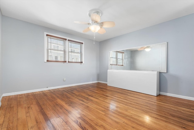 empty room featuring baseboards, a ceiling fan, and wood-type flooring