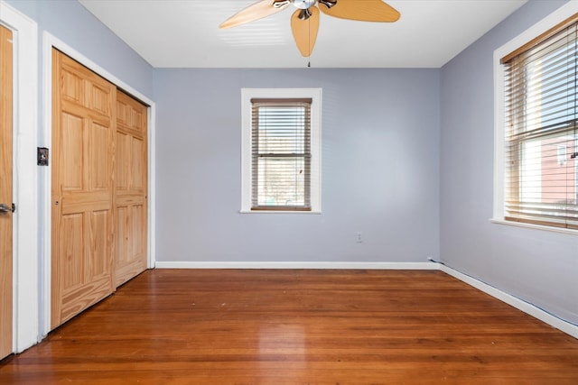 unfurnished bedroom featuring multiple windows, baseboards, and wood finished floors