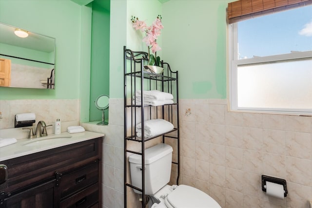 bathroom with a wainscoted wall, toilet, tile walls, and vanity