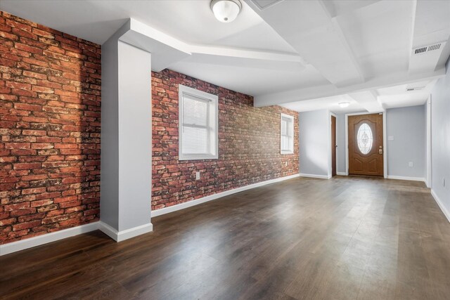 foyer entrance featuring visible vents, dark wood-style floors, baseboards, and brick wall